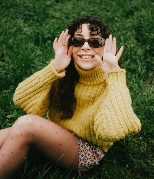 Woman feeling energetic and smiling in a bright environment.
